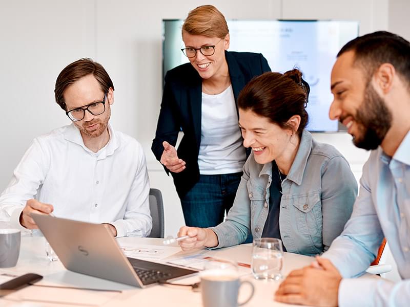 Employees together in front of a laptop